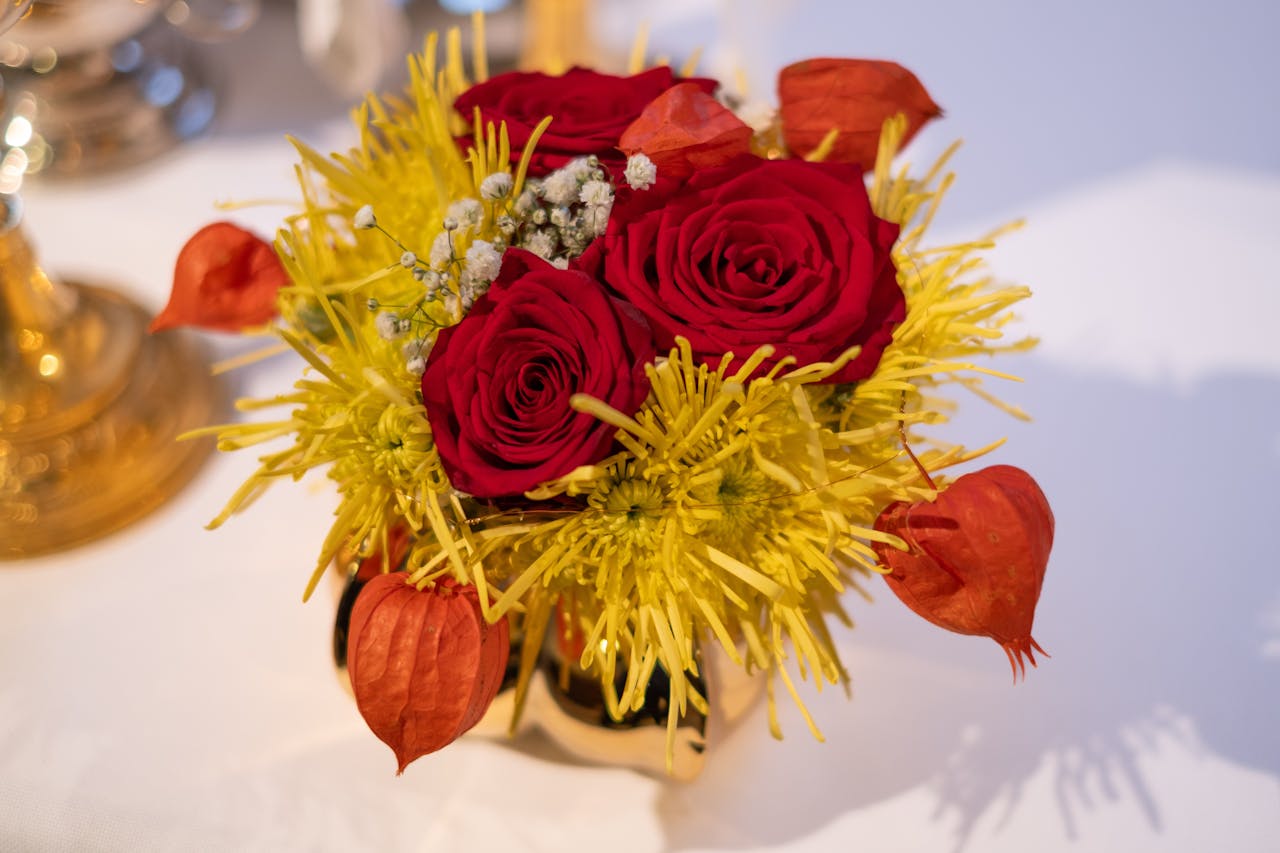 A vibrant floral arrangement with red roses and yellow blooms in a vase.