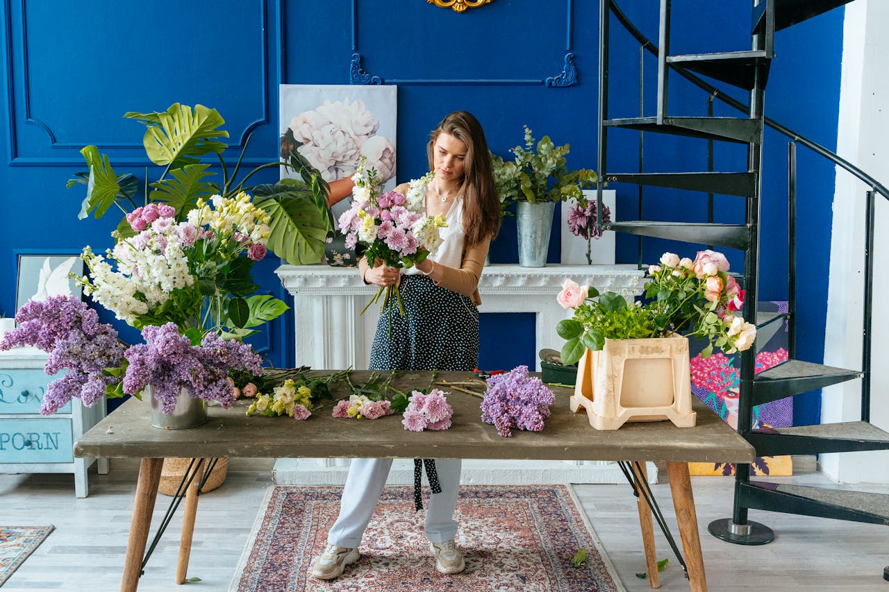 A woman florists arranges vibrant spring bouquets in a stylish indoor studio setting.